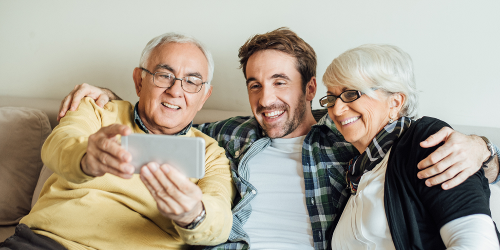 Senior couple with their adult son sitting on a couch.